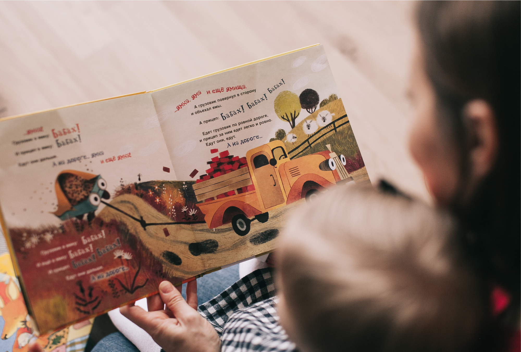 Child and adult reading a book together.