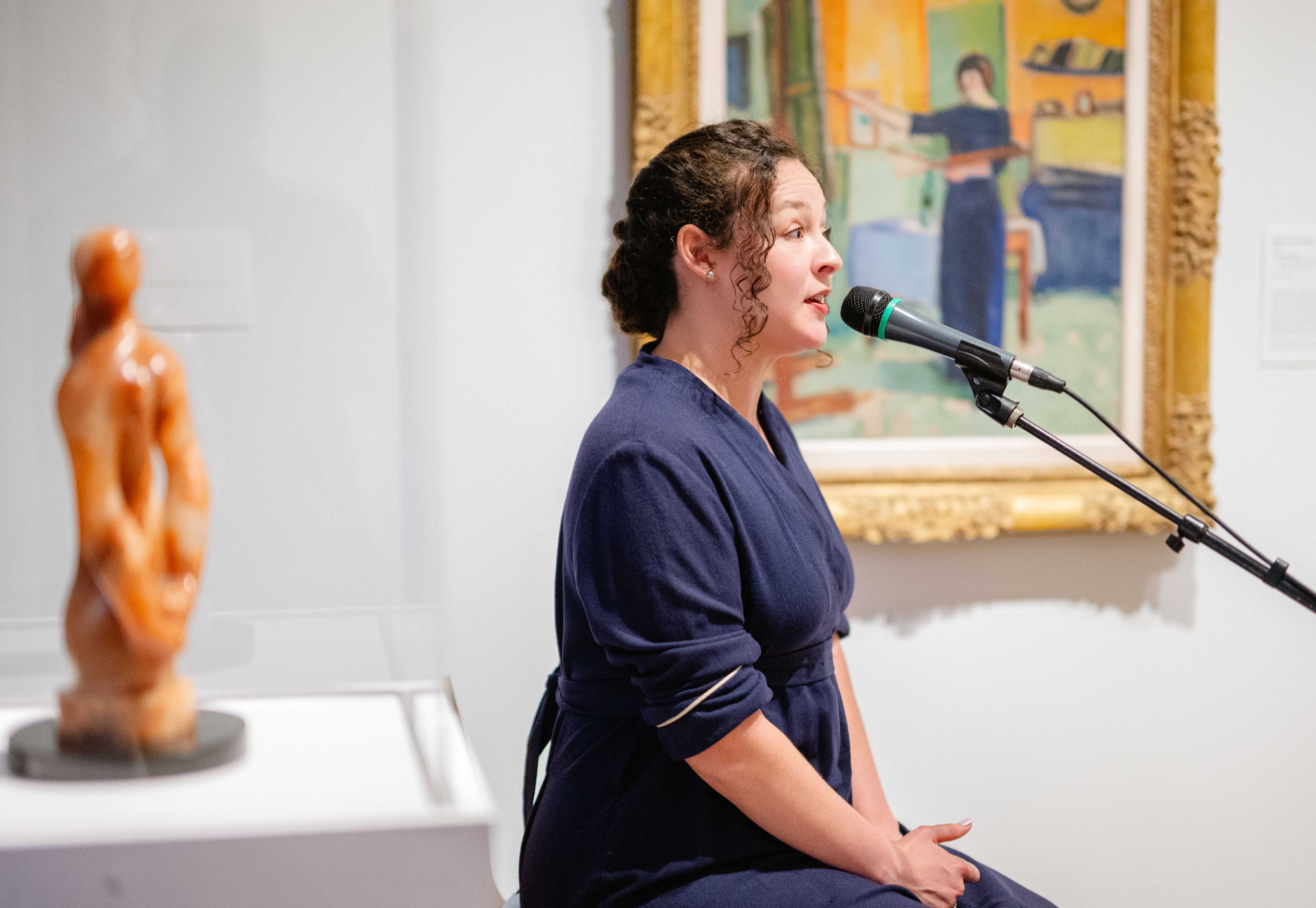 Actor in blue dress portraying artwork.